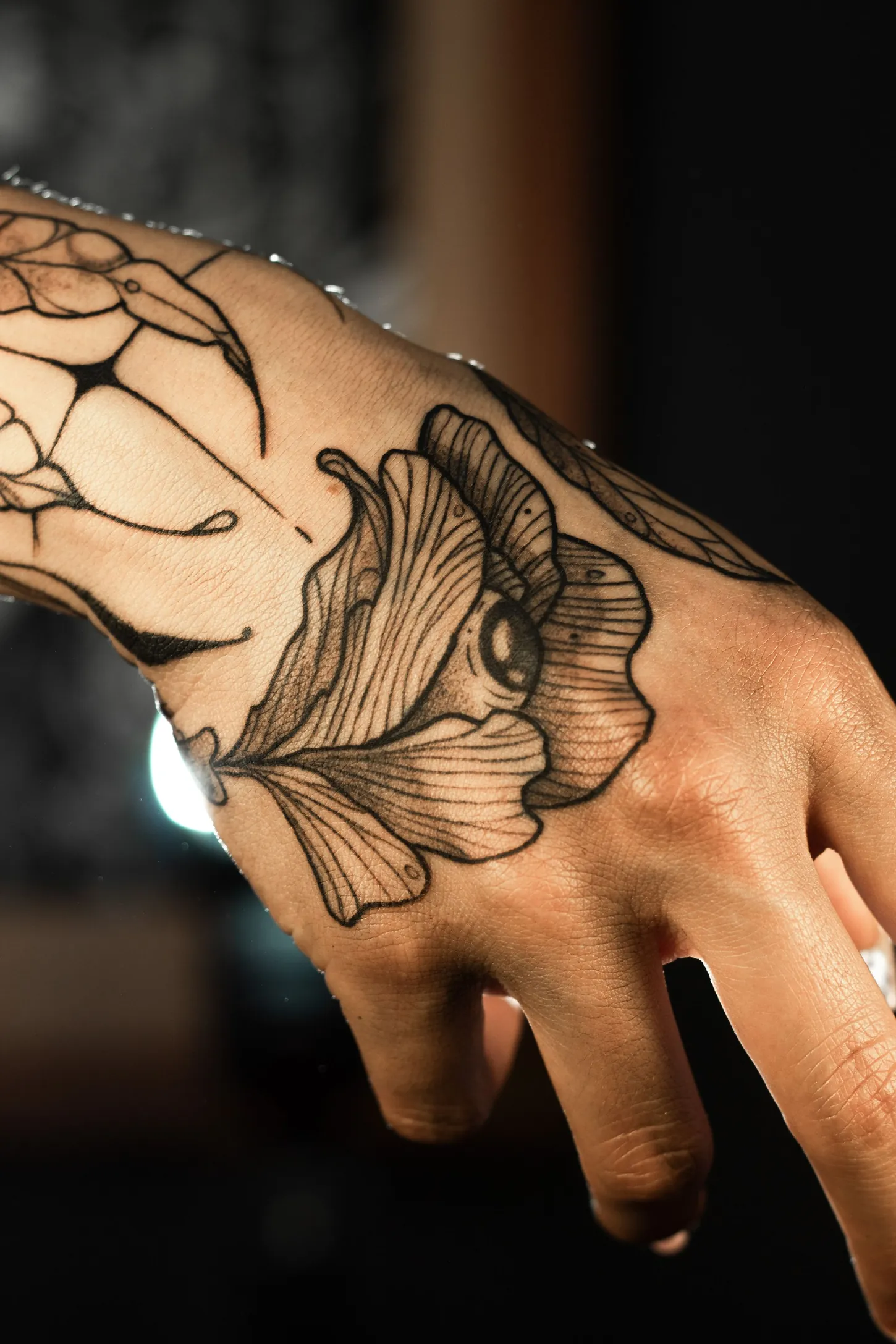 Floare ilustrativă cu un ochi în centru, tatuată pe mână